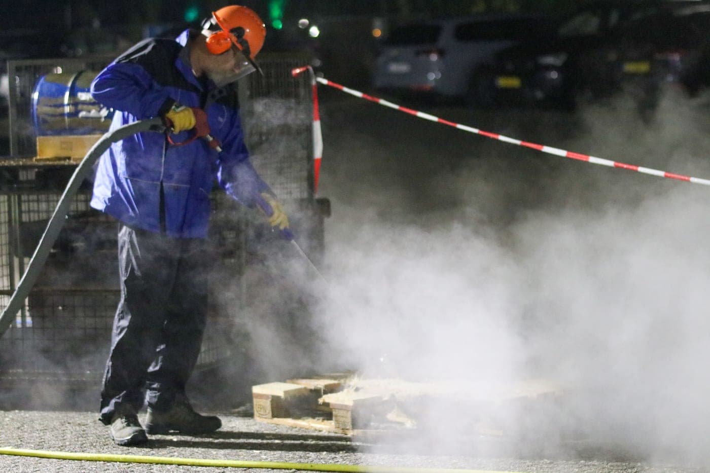 A pressure washer in use, spray lit against the dark